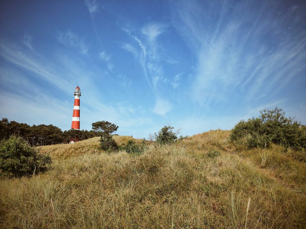 lighthouse on top of a mountain under a calm blue sky