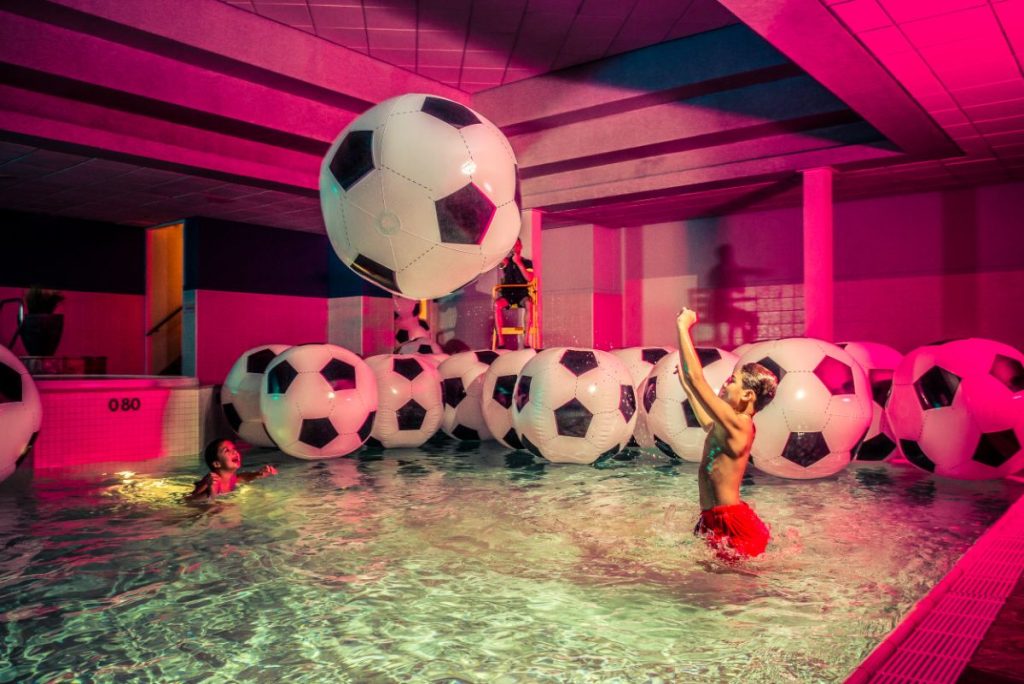 Kind in zwembad met voetballen